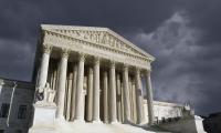 The front of the Supreme Court building with a stormy sky behind it.