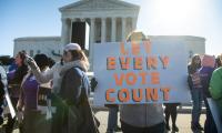 A woman holds a sign while standing outside the U.S. Supreme Court which reads "Let Every Vote Count"