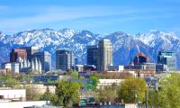 A skyline of city buildings in front of snow covered mountains