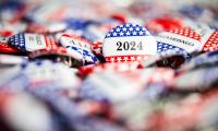 A pile of buttons with stars and stripes on them. One button in focus says "2024"