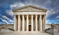 Front of the U.S. Supreme Court building under a dramatic sky with clouds