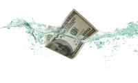 A $100 bill dropping into water against a white background