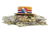 A straw hat with a red white and blue ribbon and a "Vote" button on it sitting on top of a pile of money