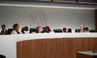 A long curved desk, behind which are sitting the FEC commissioners and their staff