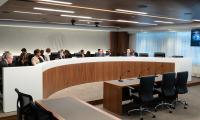 A long curved desk, behind which are sitting the FEC commissioners and their staff