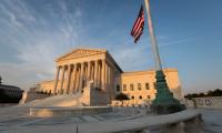 The U.S. Supreme Court in the late afternoon light with an American flag flying next to it