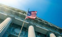 Shot looking up at the columns of a building with an American Flag flying