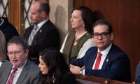 George Santos sitting among other members of Congress looking off to the side