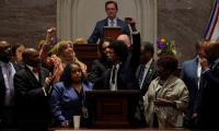 Justin Pearson raising a fist at the front of the Tennessee legislature surrounded by a group of other people