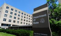 A sign saying "Department of State" in front of a plain concrete building with windows