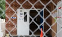 The open door of a polling place seen through a chain link fence