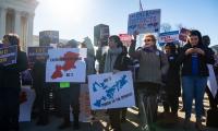 A group of protesters holding signs stands in a line