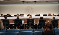 FEC commissioners sit behind a desk facing five people seated in chairs at a desk in front of them.