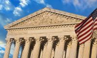 The front of the U.S. Supreme Court with an American flag flying