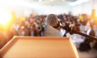 A microphone at a podium overlooking an audience out of focus in the background