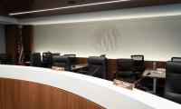 Chairs behind a desk with a large logo of the FEC on the wall behind them