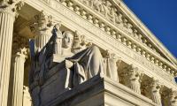 A statue in front of the columns of the Supreme Court building