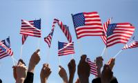 Group of People Waving American Flags over blue sky. Adobe Stock image.