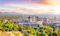 A view of the buildings in Salt Lake City with the mountains and sun behind them