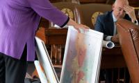 A woman sorts through a stack of large poster prints of maps