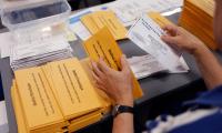 A person's hands removing ballots from envelopes
