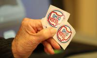 A person's hand holding two stickers that say "Ohio Voted"