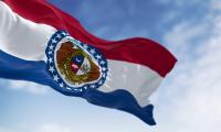 State flag of Missouri waving against a blue sky with white clouds
