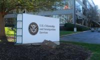 A sign with the Department of Homeland Security seal and the word U.S. Citizenship and Immigration Services in front of an office building