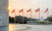A shot from the Washington Monument frames the Capitol Building with American flags during sunset.