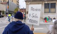A man holds a sign that says "Pardons 4 Sale $1,000,000."