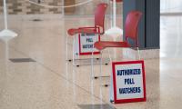 Two empty chairs and two signs that say "Authorized Poll Watchers".