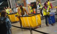 People move large yellow bins full of ballots