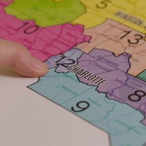 A finger pointing to a district on a map of North Carolina