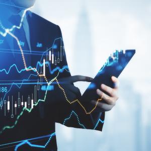 A man in a suit holds a phone with a stock graph overlaid on top