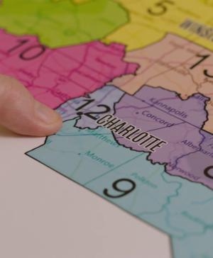A finger pointing to a district on a map of North Carolina