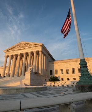 The U.S. Supreme Court in the late afternoon light with an American flag flying next to it