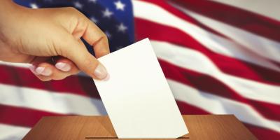 Voter's hand placing ballot into box