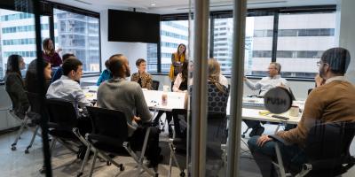 People sit around a table in a conference room seen through an open glass door