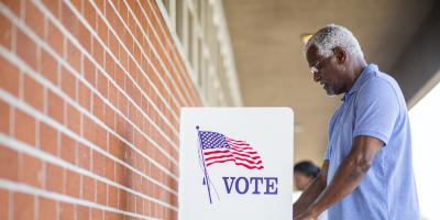 A black man votes at a voting booth