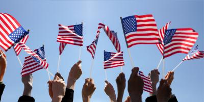 Group of People Waving American Flags over blue sky. Adobe Stock image.