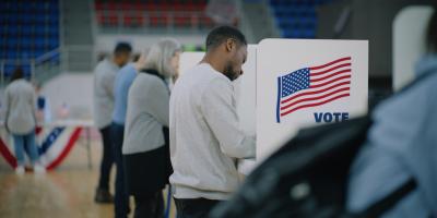 Man stands in front of voting booth.