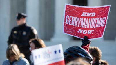 A concerned citizen holds a sign that says End Gerrymandering Now