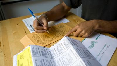 Shot of a person's hands at a table filling out an absentee ballot