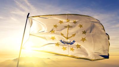 The state flag of Rhode Island with the sun shining behind it
