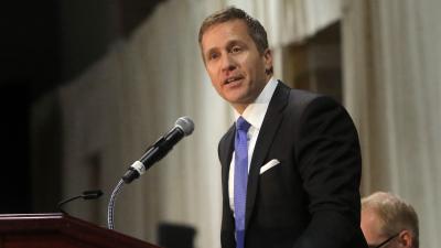 Eric Greitens speaking into a microphone at a podium.