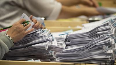 A woman's hands counting a stack of ballots