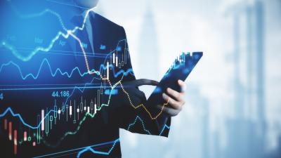 A man in a suit holds a phone with a stock graph overlaid on top