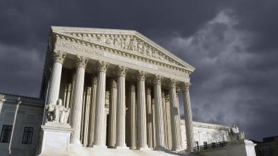The front of the Supreme Court building with a stormy sky behind it.