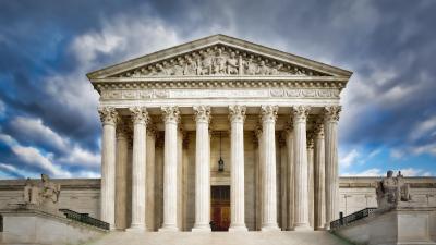 Front of the U.S. Supreme Court building under a dramatic sky with clouds