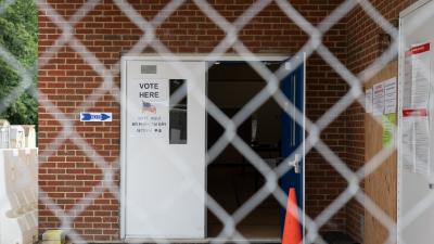 The open door of a polling place seen through a chain link fence